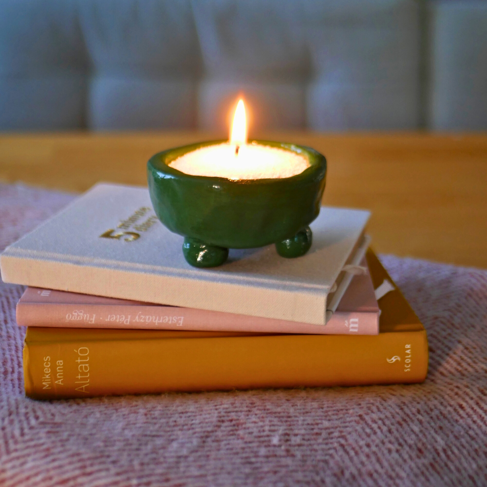 zöld diy homokgyertya egy könyvkupac tetején 
